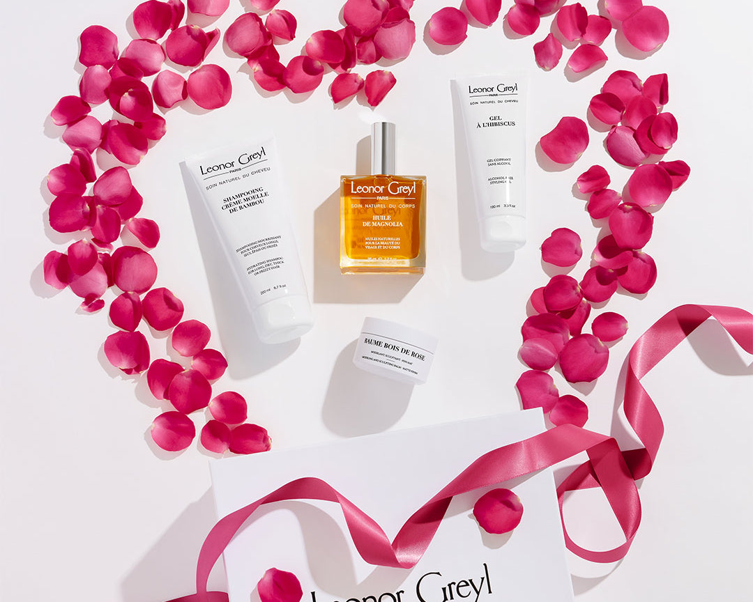 Leonor Greyl hair products surrounded by pink petals and pink ribbon in the shape of a heart