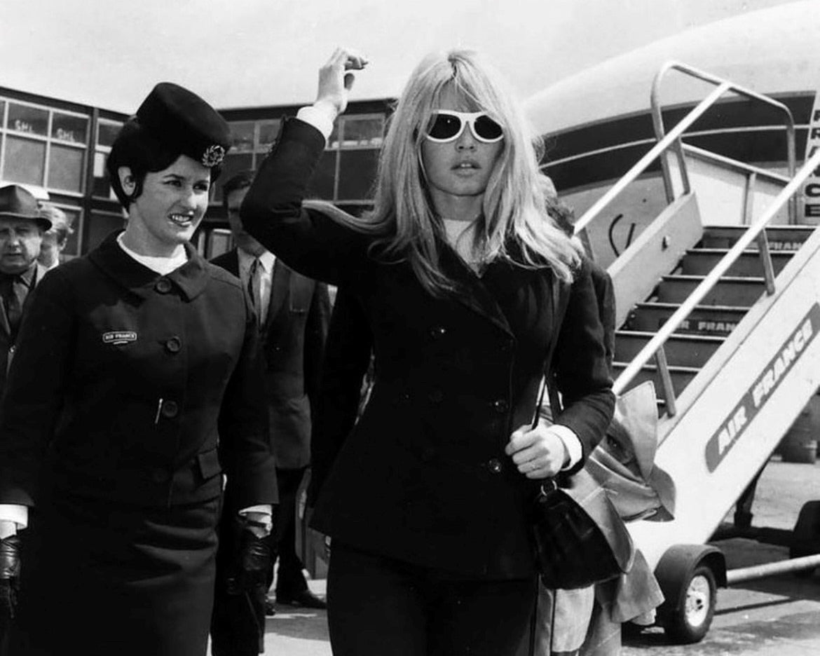 glamorous woman in sunglasses walking away from an airplane