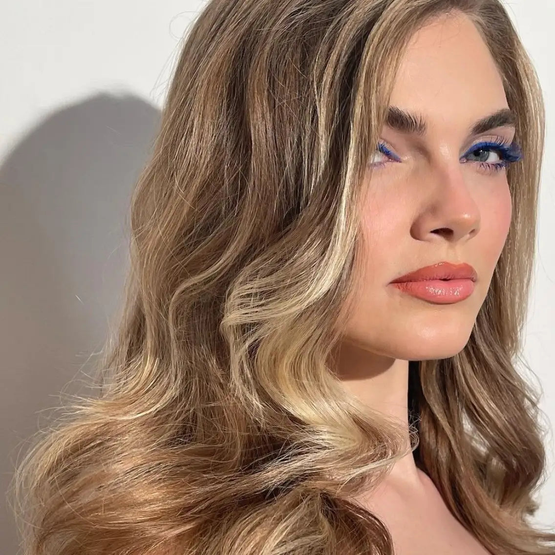 Woman looking sideways at camera with beautiful, big, bombshell waves in her blonde hair