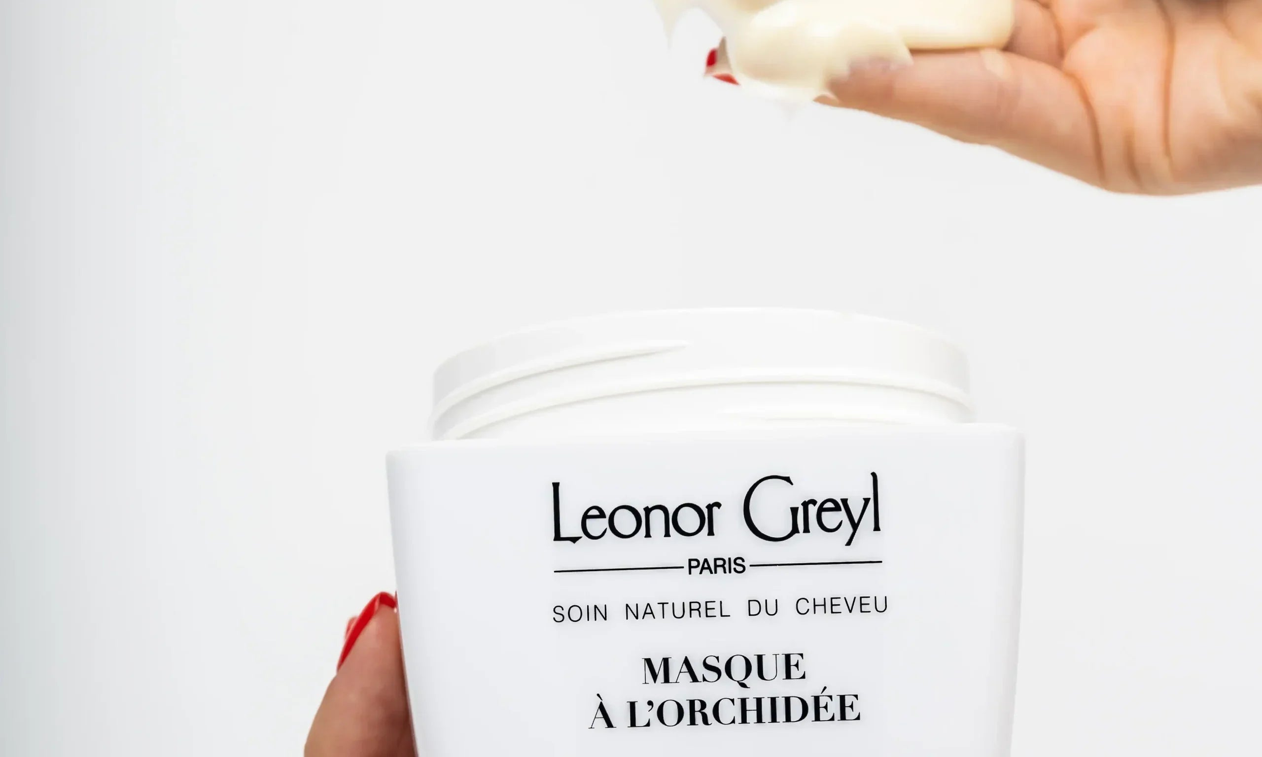 woman's hands with red nails scooping masque à l'orchidée out of a leonor greyl container
