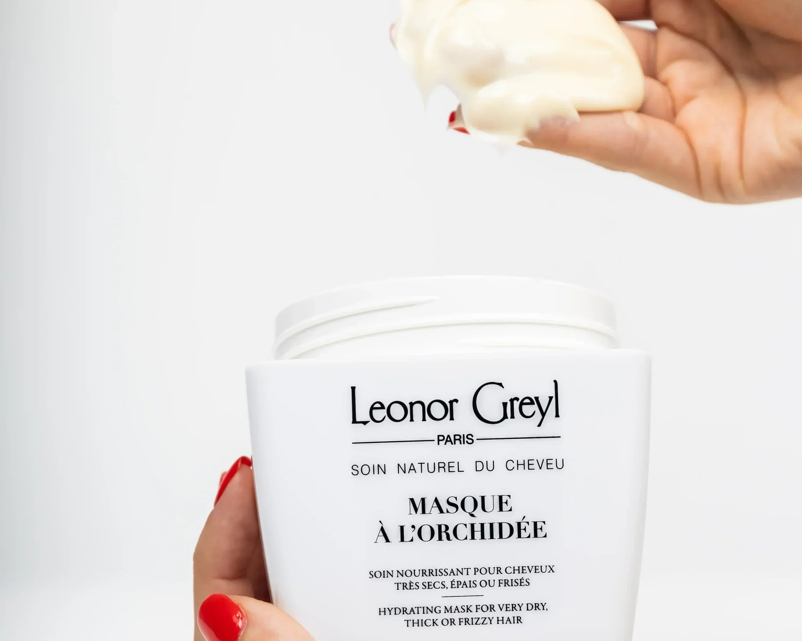 woman's hands with red nails scooping masque à l'orchidée out of a leonor greyl container