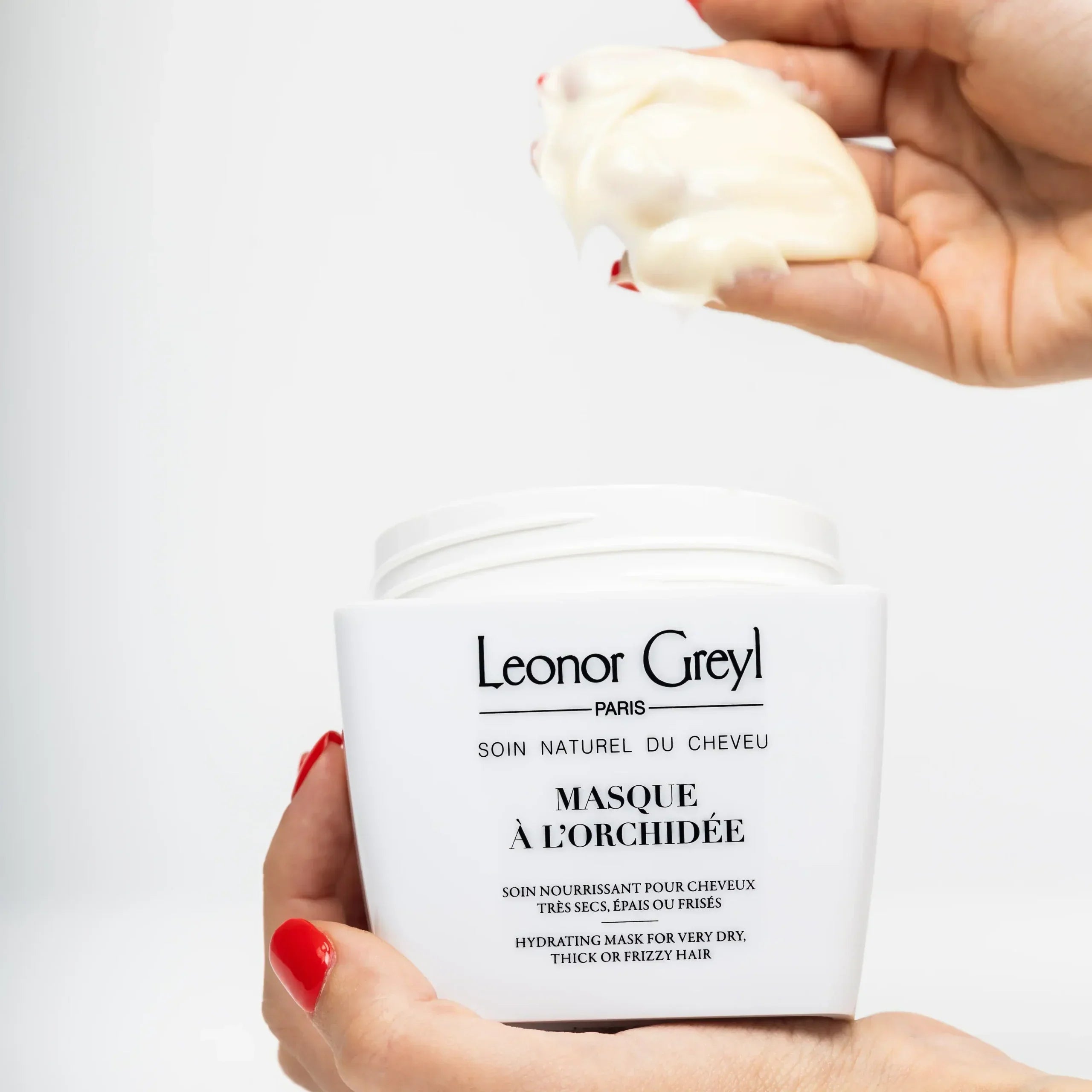woman's hands with red nails scooping masque à l'orchidée out of a leonor greyl container