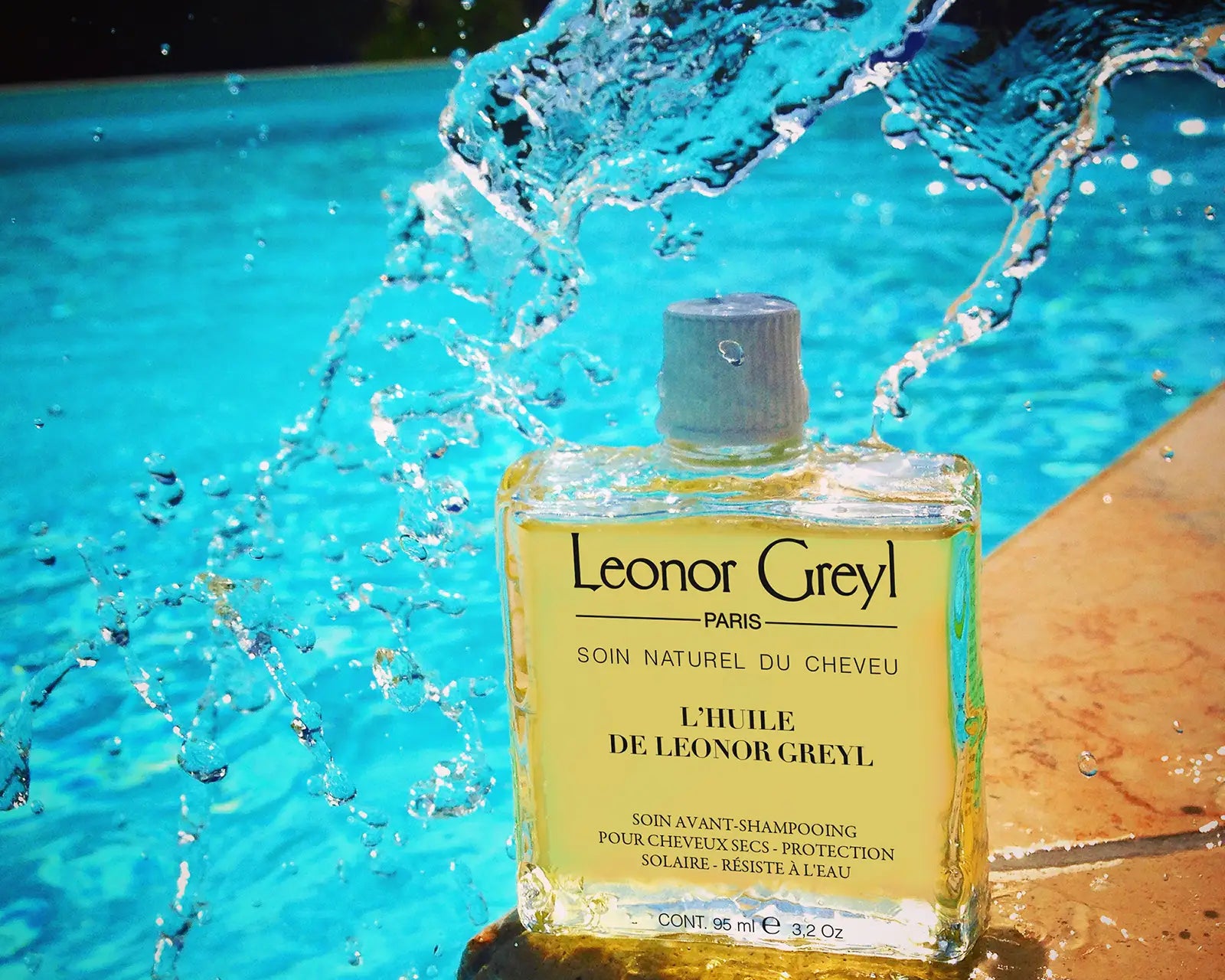 L'Huile de Leonor Greyl poolside with blue water splashing