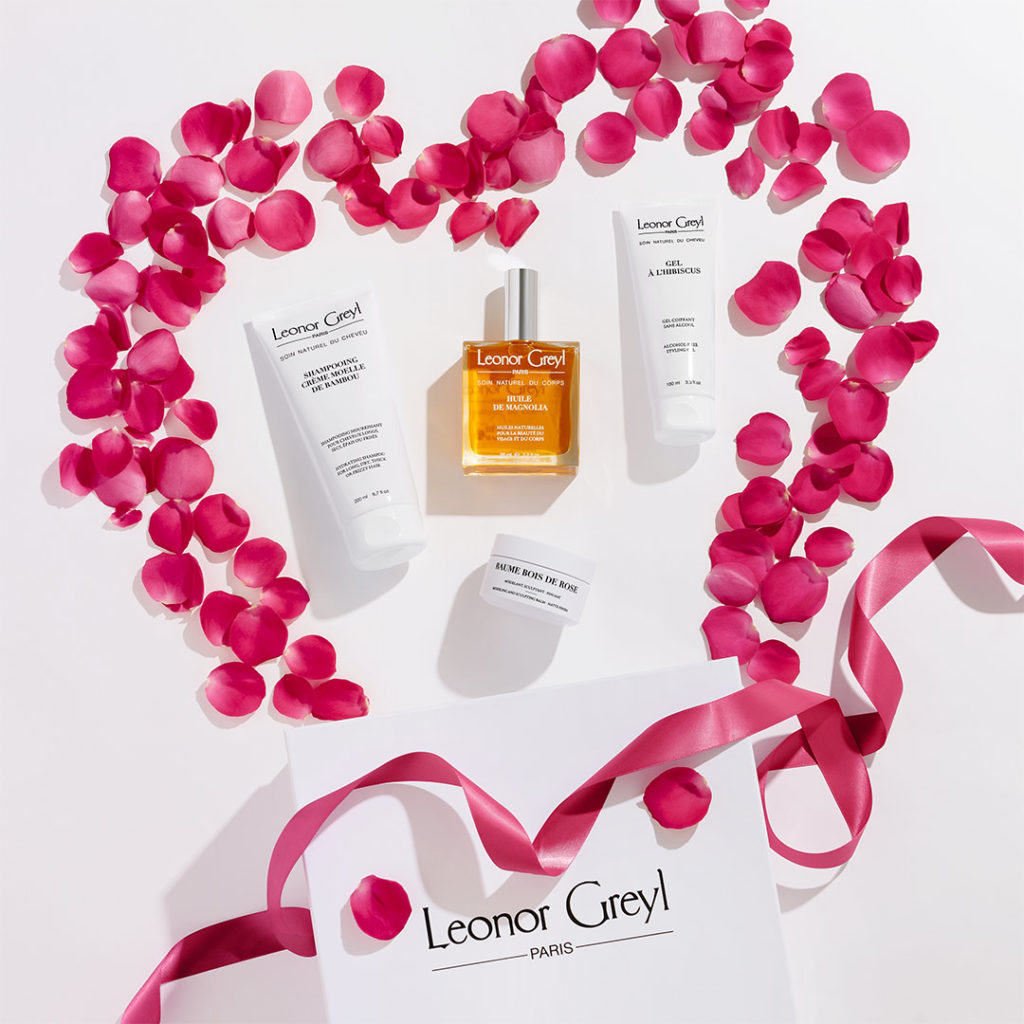 Leonor Greyl hair products surrounded by pink petals and a pink ribbon, forming the shape of a heart