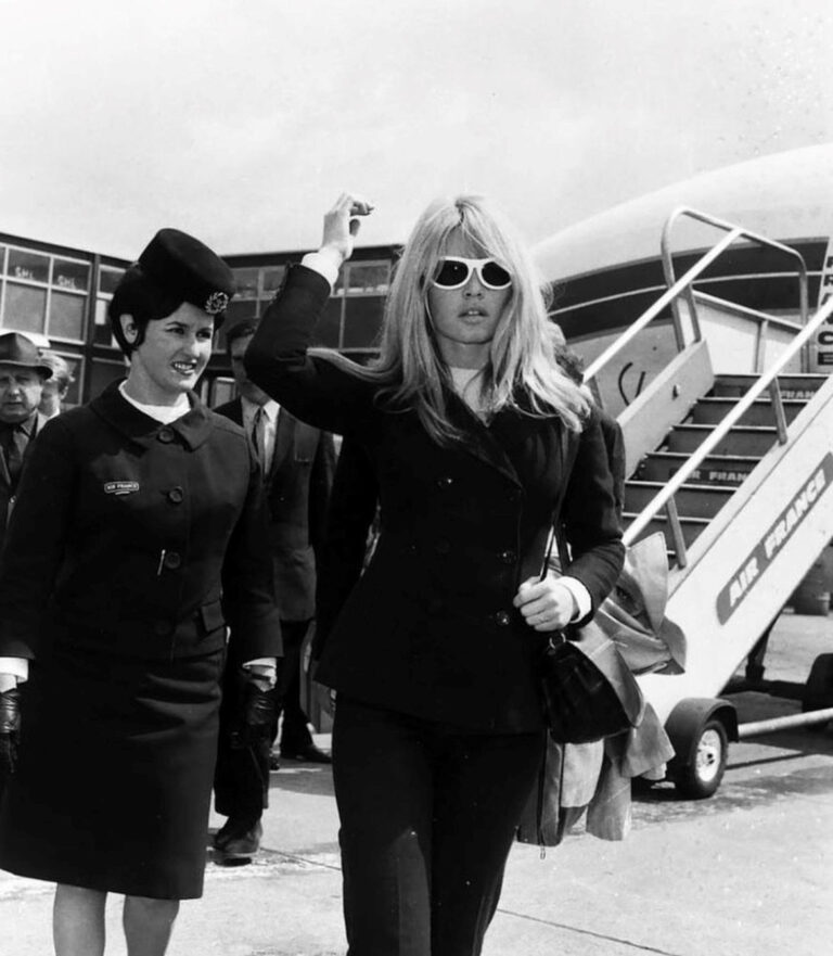 glamorous woman in sunglasses walking away from an airplane