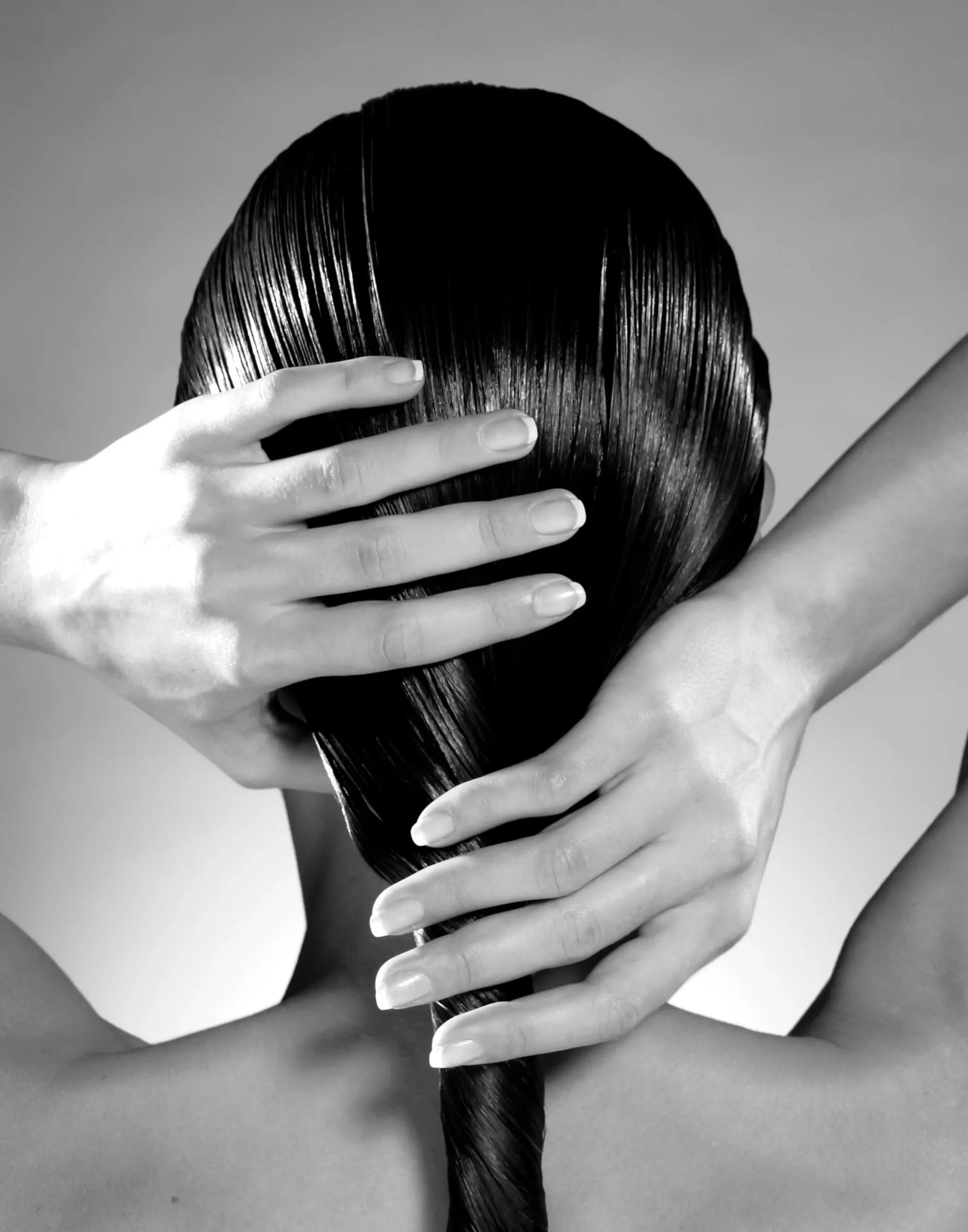 black and white back view of a woman holding her dark wet hair