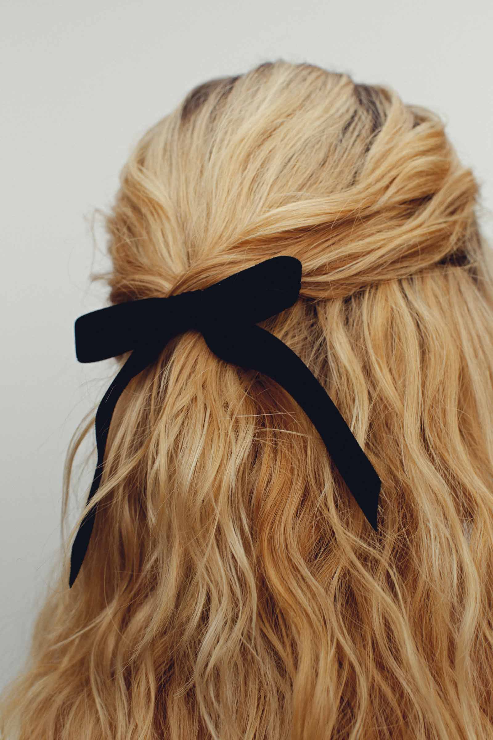 closeup of henningson black bardot bow in wavy blonde hair