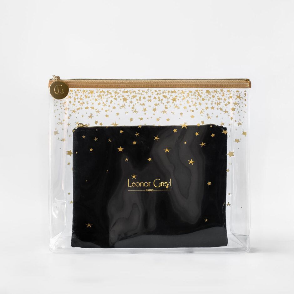 Clear plastic pouch with gold stars and zip seal and black Leonor Greyl item inside