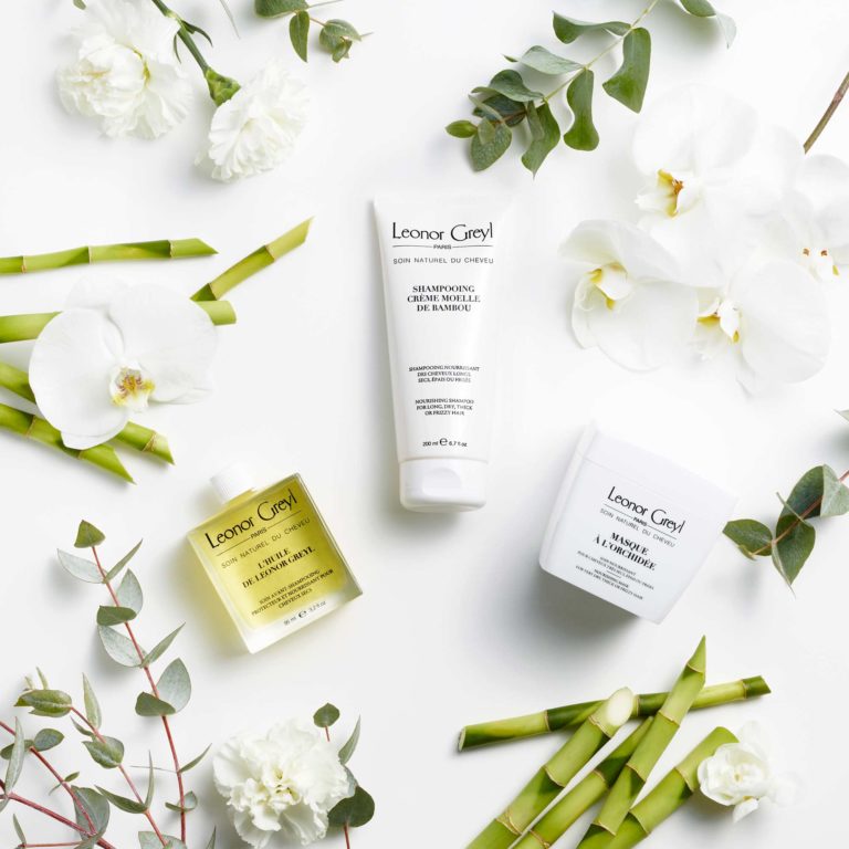 leonor greyl products on white background with bambou, flowers, and greenery