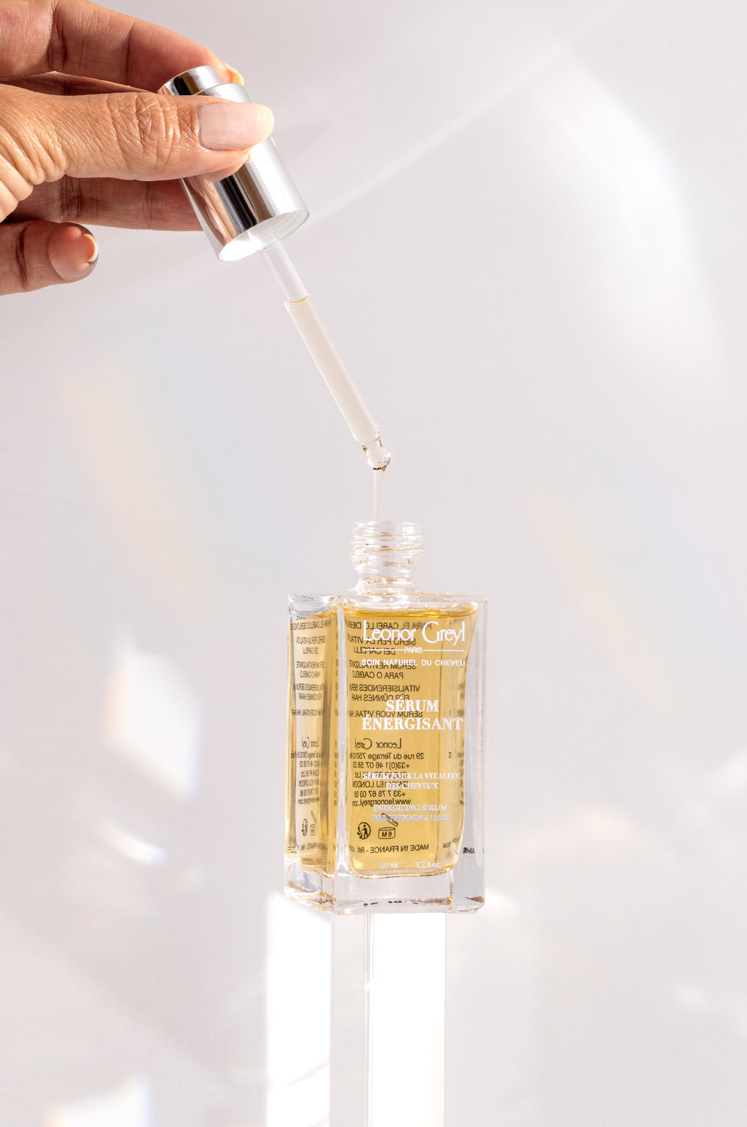 Hand squeezing a dropper of Leonor Greyl Serum Energisant