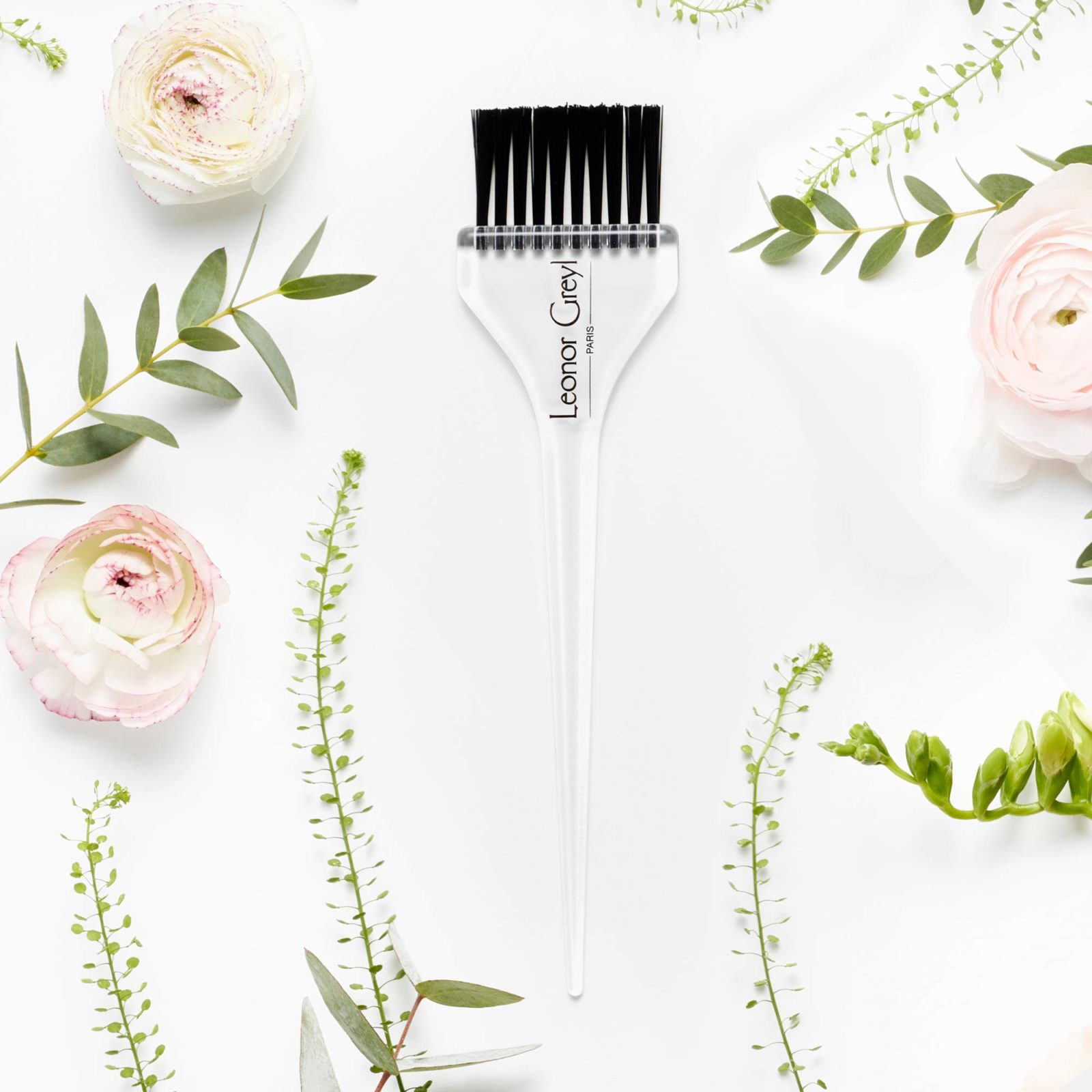 leonor greyl at home treatment brush amongst pink flowers and greenery